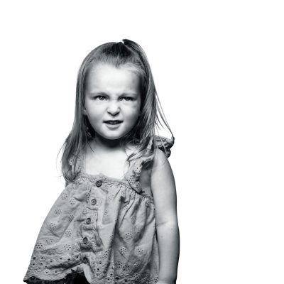 Black and white portrait of a playful young girl showing confidence and childhood charm.