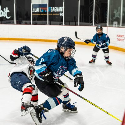 Young hockey players compete intensely for the puck on a bright, fast-paced ice rink.